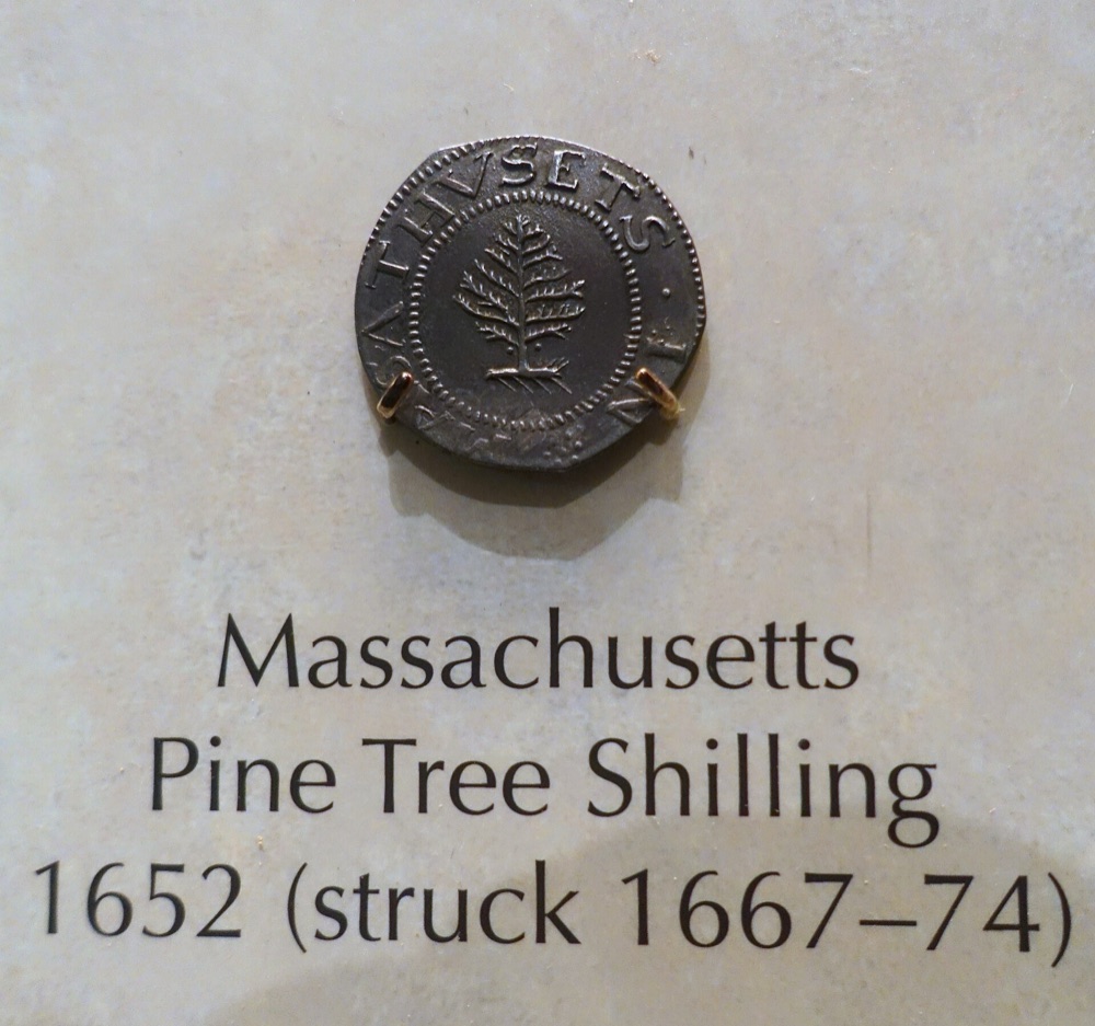1652 Massachusetts Pine Tree shilling, obverse with pine tree, on the Smithsonian's exhibit mount labeled 'struck 1667-74' (the large-planchet period) — the Smithsonian's example of the same issue; the tracked PCGS MS65 specimen is a different coin
